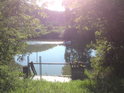 Stavidlo na levém břehu Moravy v Otrokovicích, po řece pluje motorový člun a zalévají ji sluneční paprsky.