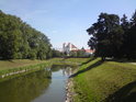 Pohled proti klidnému toku Moravy ve Veselí. Po obou březích je zámecký park, v pozadí pak lávka a kostel Svatých Andělů Strážných.
